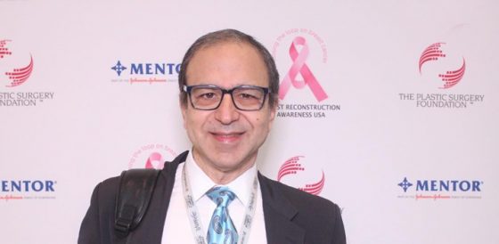 Dr. Rodriguez standing in front of a breast reconstruction awareness backdrop at a plastic surgery conference